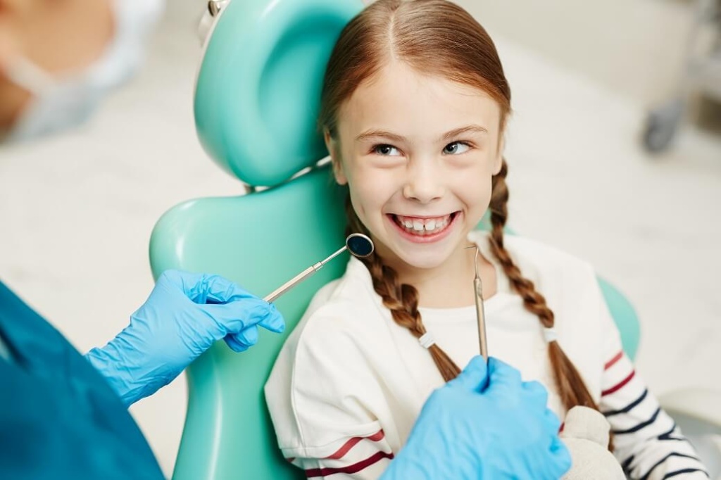 девочка улыбается на приеме у стоматолога